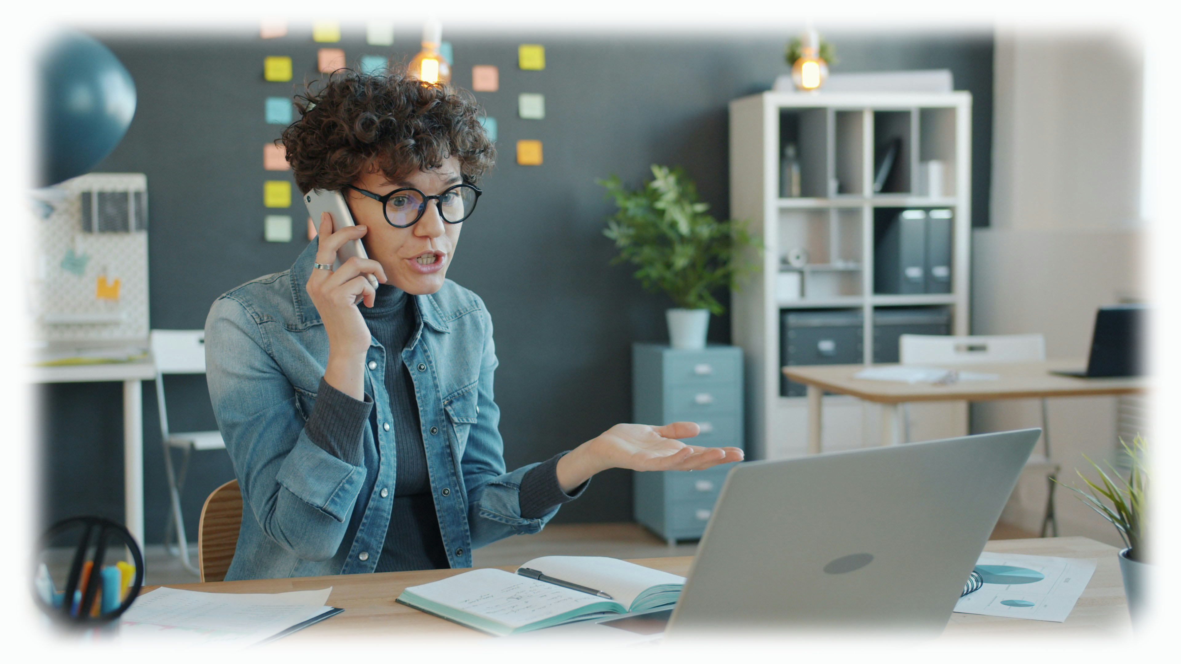 Telefonierende Frau im Büro vor Laptop